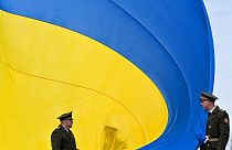 FILE - Ukrainian servicemen hold a huge national flag  near Kyiv, on March 31, 2023.
