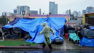Homeless people use plastic tarps to shield themselves from a light rain brought by Tropical Storm Hilary in downtown San Diego, Sunday, Aug. 20, 2023. 