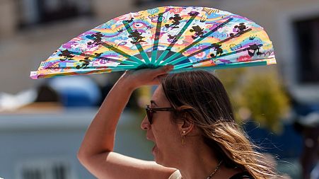 A woman protects herself with a hand-held fan from the sun in Madrid, Spain, July 2023. 