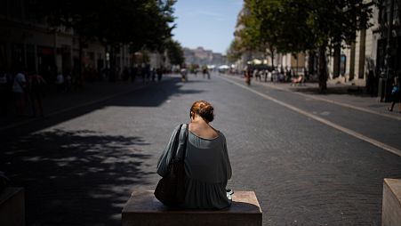 A woman sits in the shade in high temperatures in Marseille, southern France, Saturday, Aug. 19, 2023. (AP Photo/Daniel Cole)